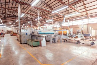 Vista ampla do interior organizado de uma fábrica brasileira, com máquinas industriais modernas.