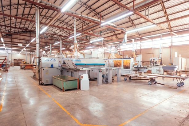 Vista ampla do interior organizado de uma fábrica brasileira, com máquinas industriais modernas.