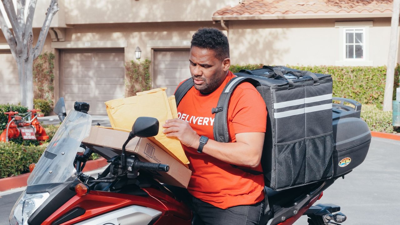 Entregador transporta encomendas em uma motocicleta durante o trabalho.