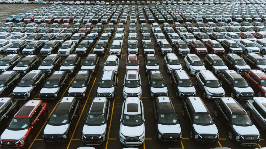 Vista aérea de um grande pátio com milhares de carros estacionados em fileiras.